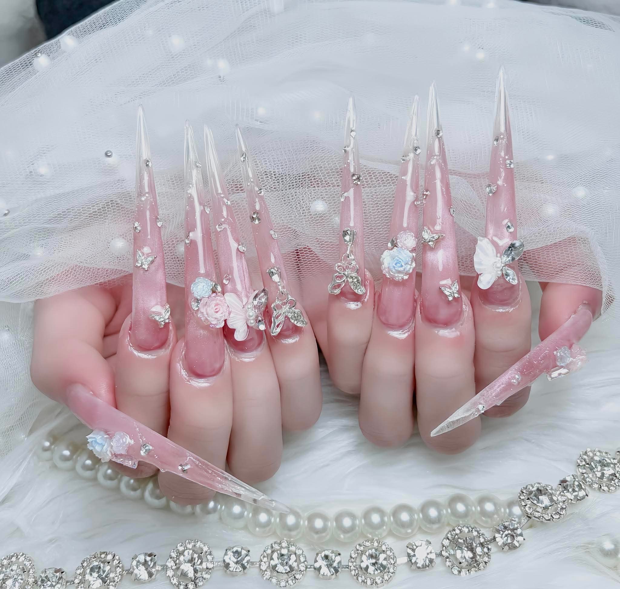 Extra-long pink nail extensions with crystal and flower details